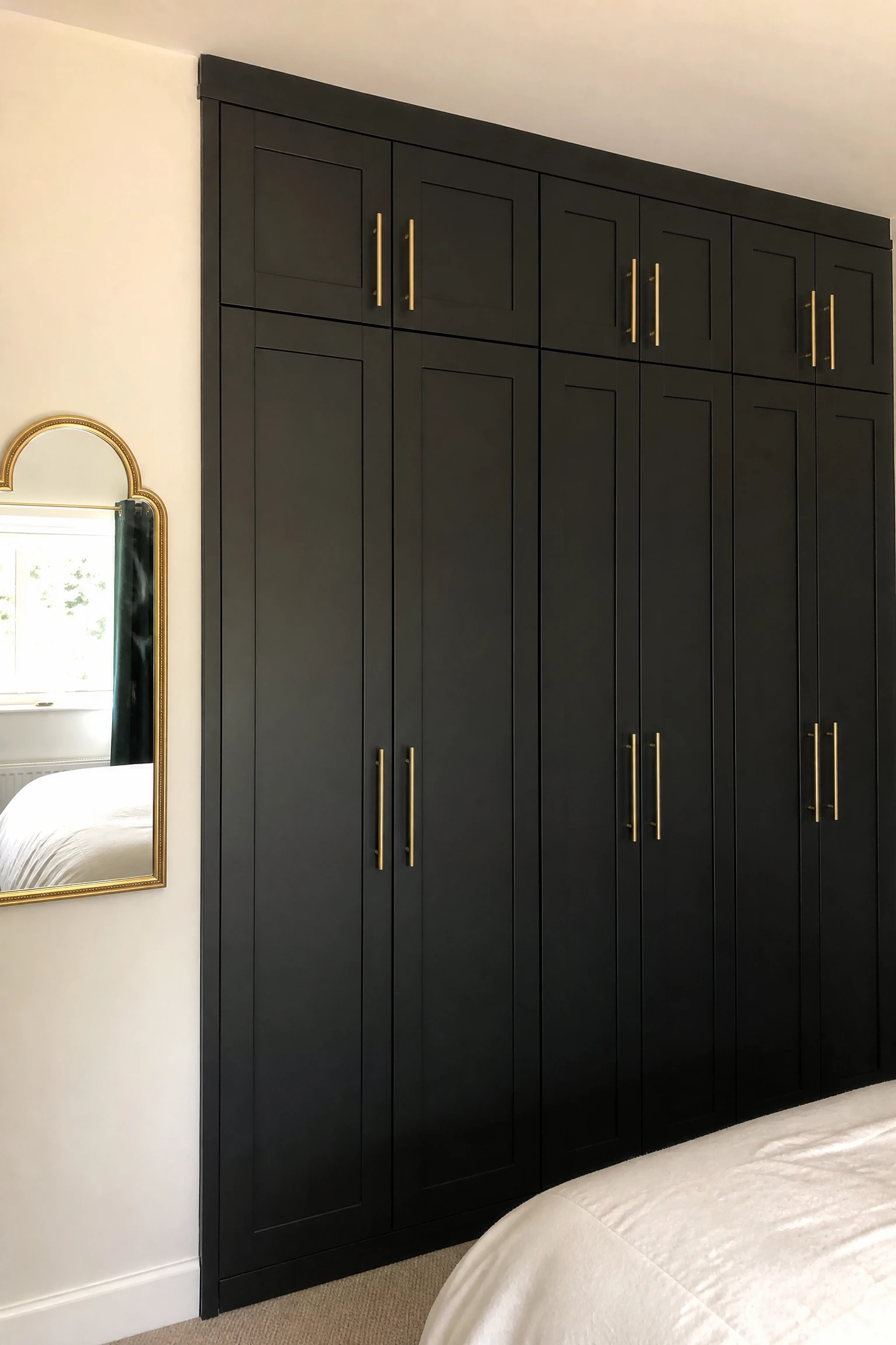 the built-in wardrobe looks like a standard rental fixture: add gold handles and black paint in a bedroom