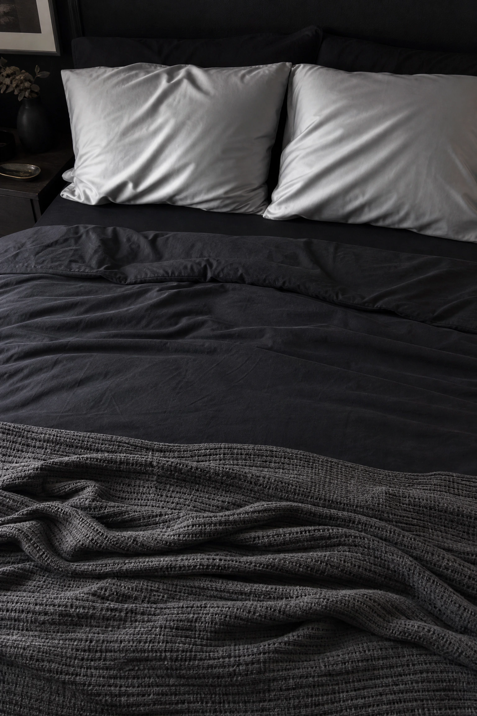 black and charcoal layered bedding with silver pillowcases in a bedroom