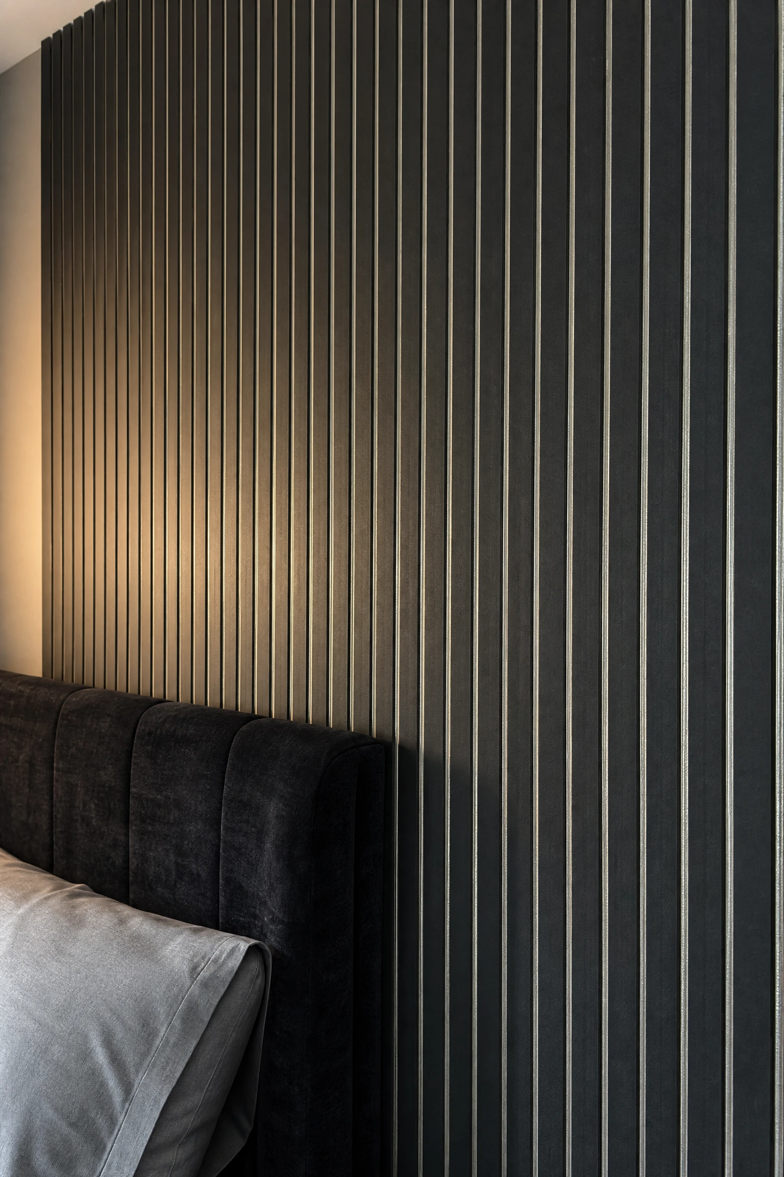 black fluted panel wall with silver grout lines in a bedroom