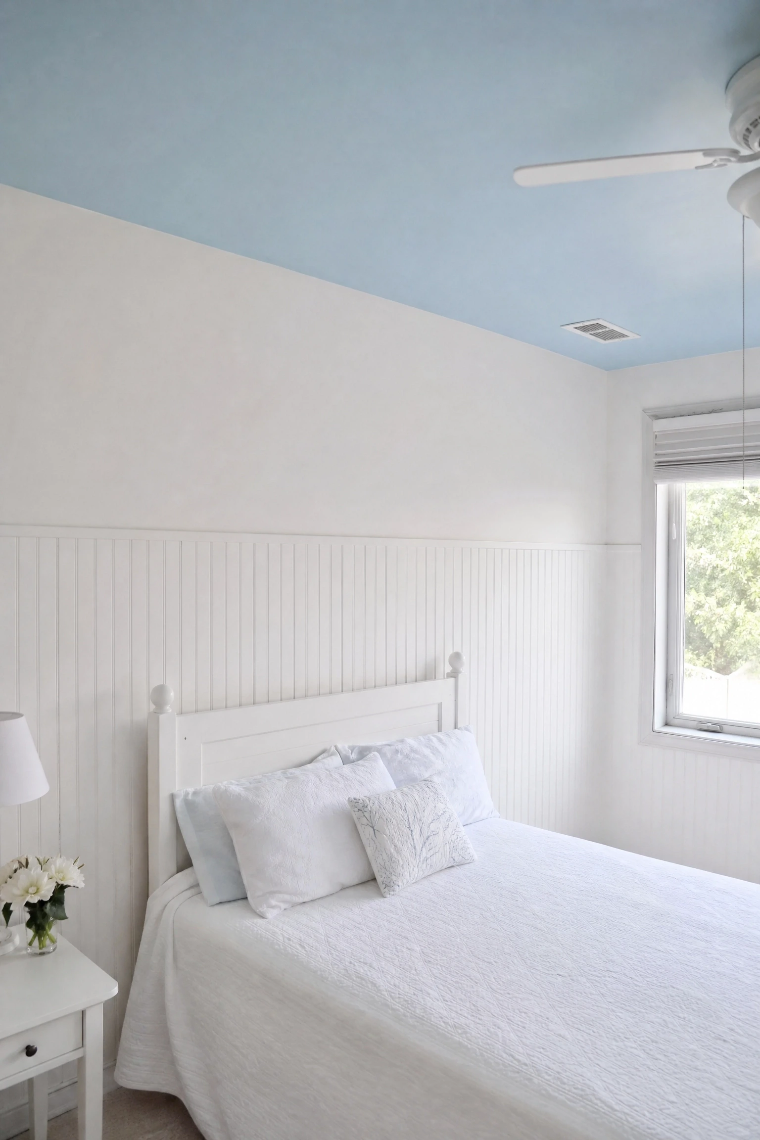 sky blue ceiling with wooden beadboard below in a bedroom