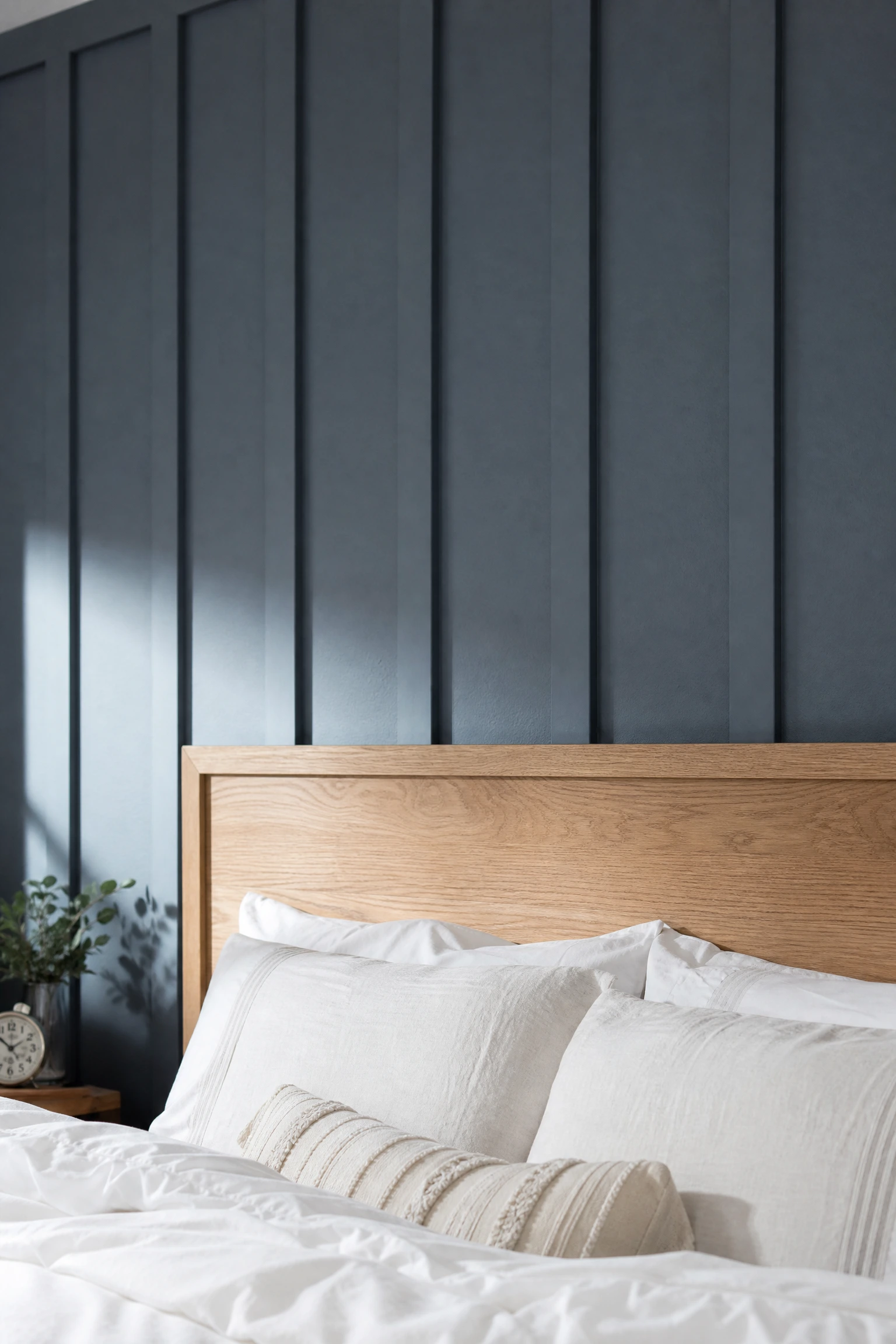 slate blue paneled wall behind a raw oak headboard in a bedroom