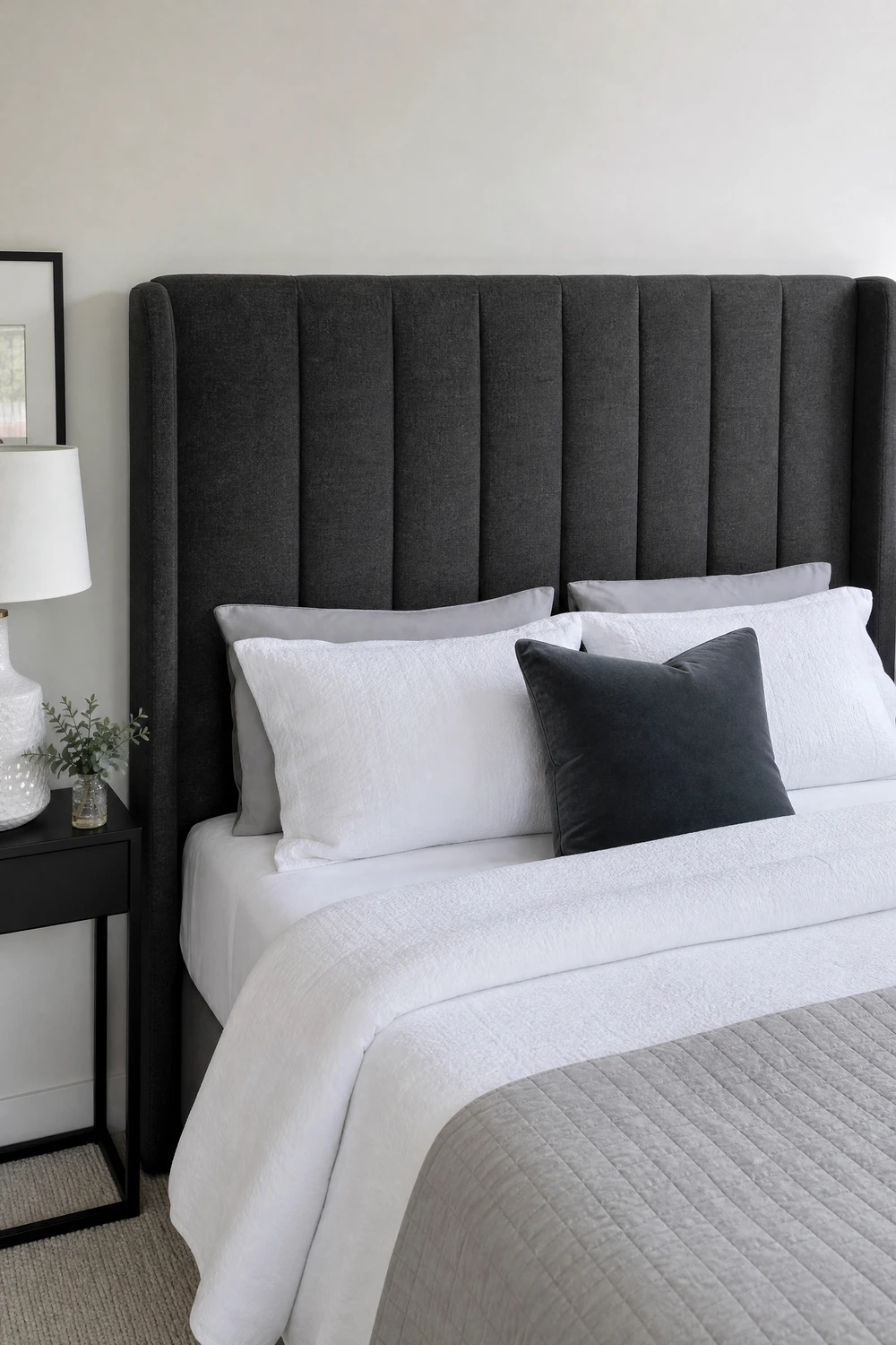 white walls with a charcoal upholstered headboard in a bedroom