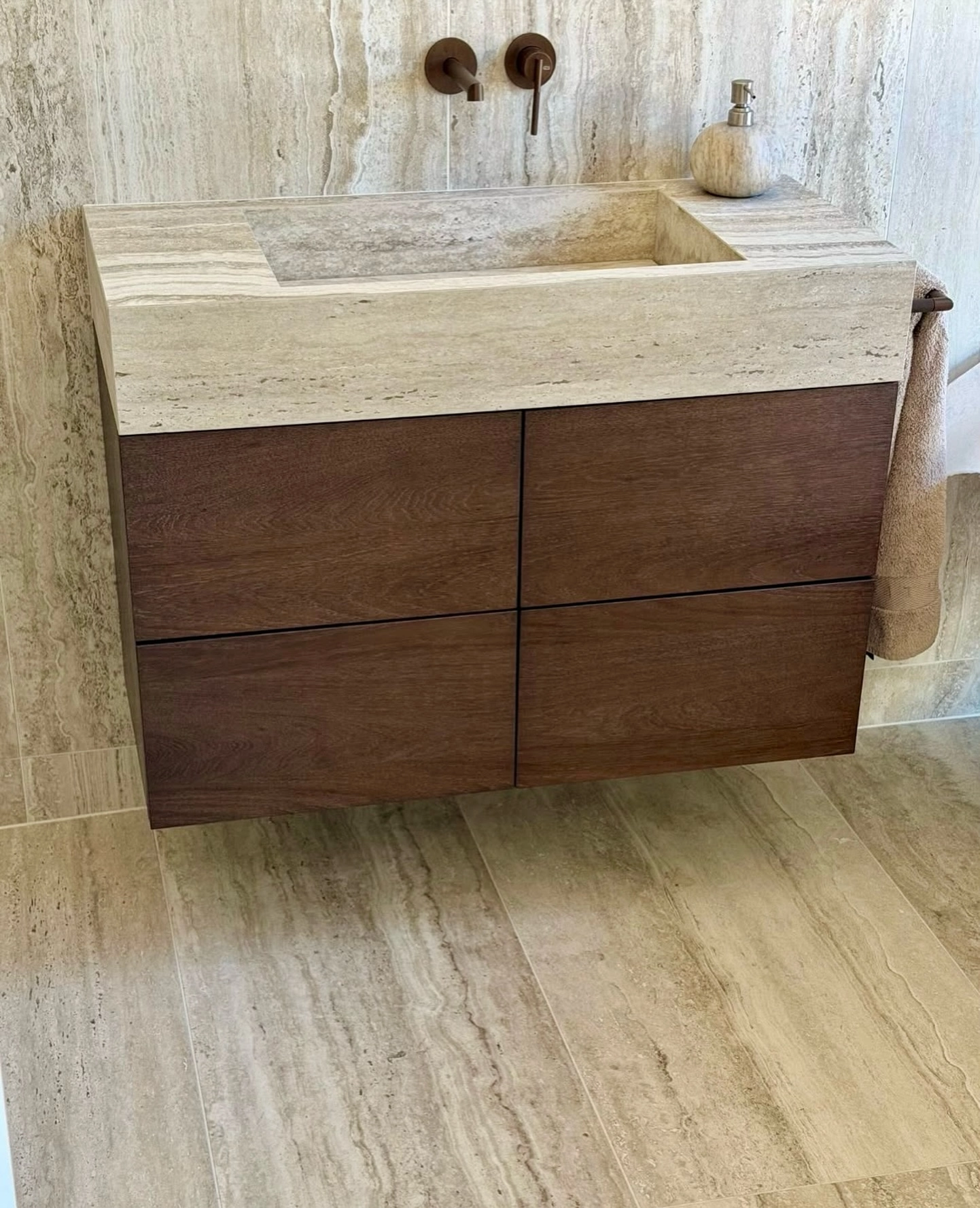 Dark wood vanity with a beige travertine stone top