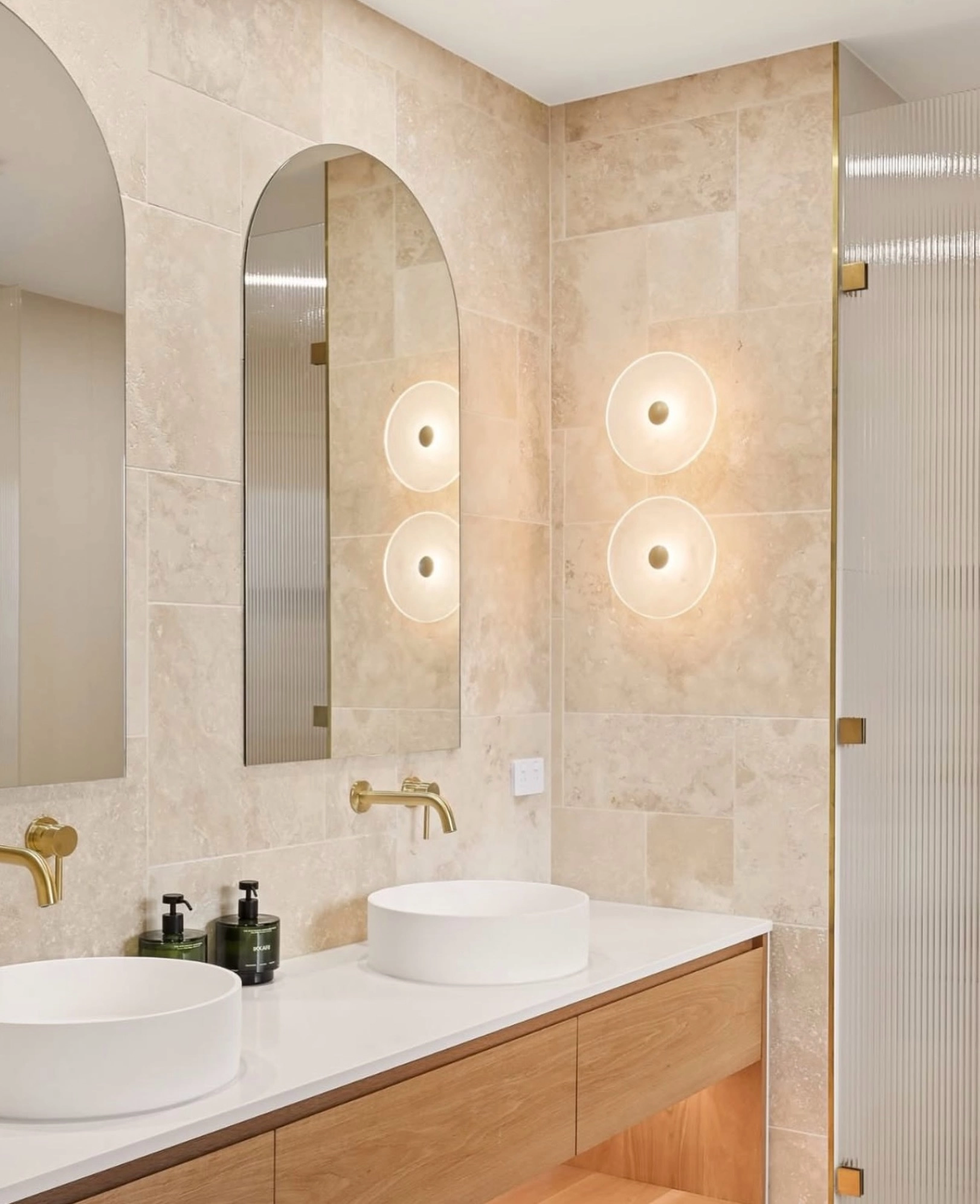 Warm round wall lights glowing over beige travertine tiles