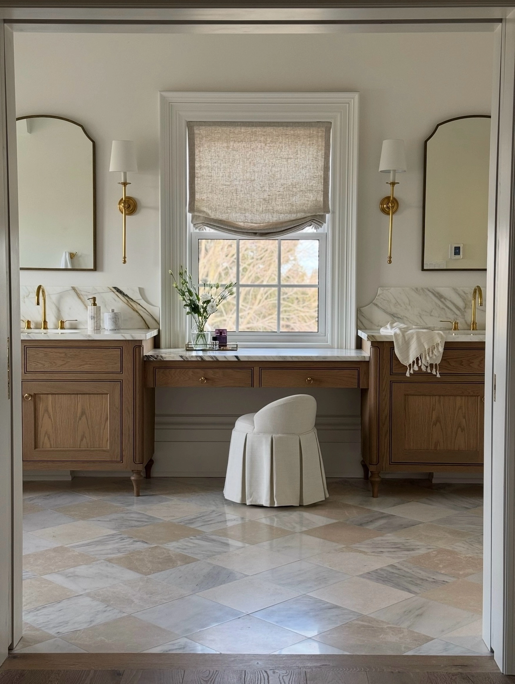 Bathroom seen through a doorway with oak vanities and beige floor tiles